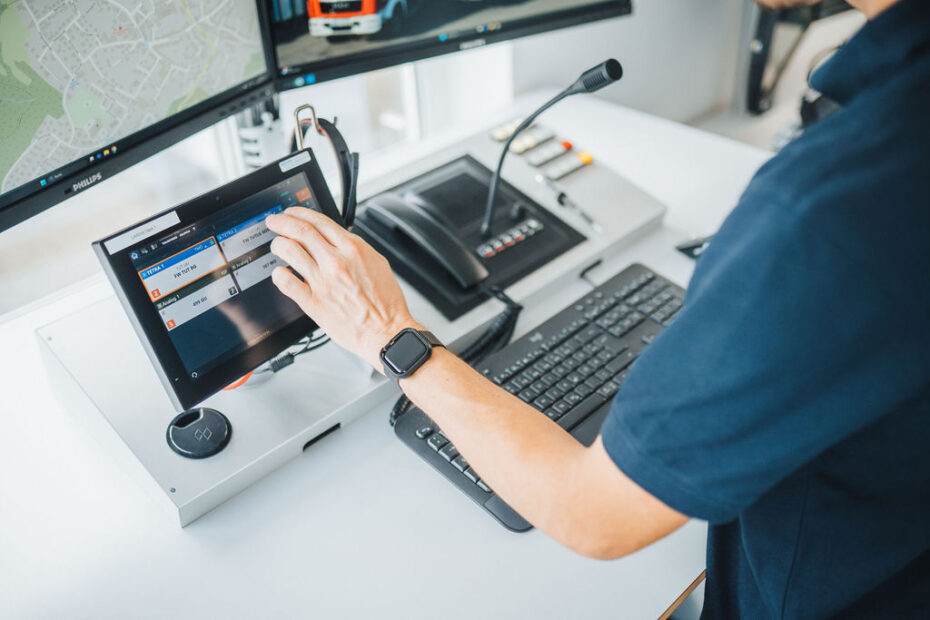 Benutzer bedient das LARDIS-System über einen Touchscreen in der Funkzentrale, unterstützt durch ergonomische Arbeitsstation mit höhenverstellbarem Tisch.